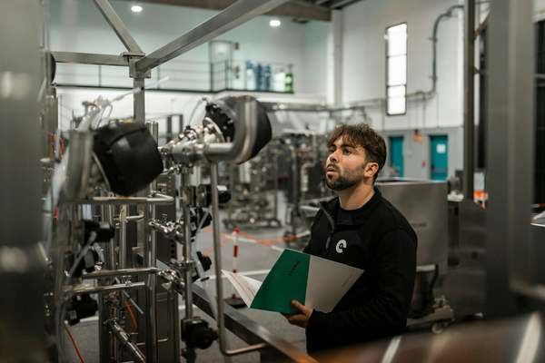 An auditor with a folder inspecting a production line