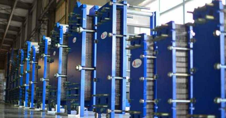 Rows of blue plate heat exchangers with tie bolts standing in a manufacturing hall