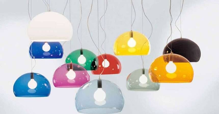 Row of coloured translucent pendant lamps with exposed bulbs hanging at different heights