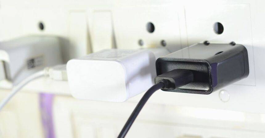 White and black USB power adapters plugged into a wall socket with a charging cable