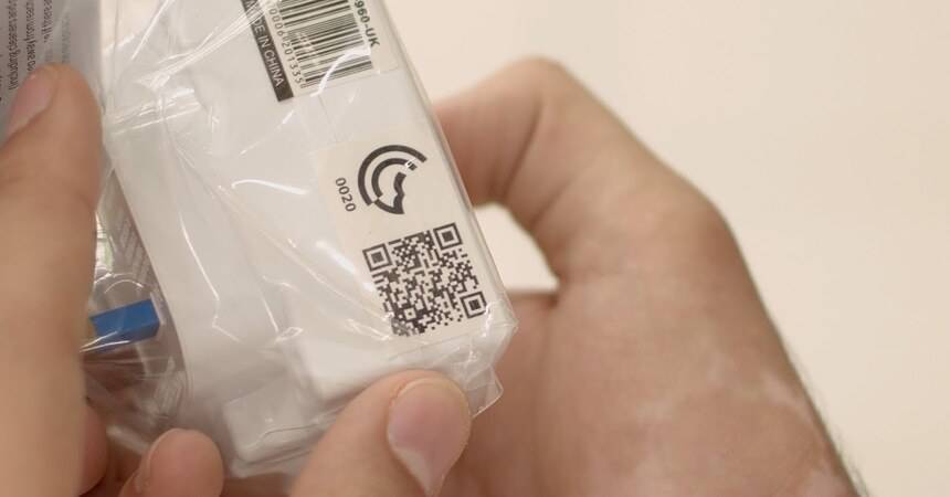 Hands holding a packaged product with a conformity label and QR code