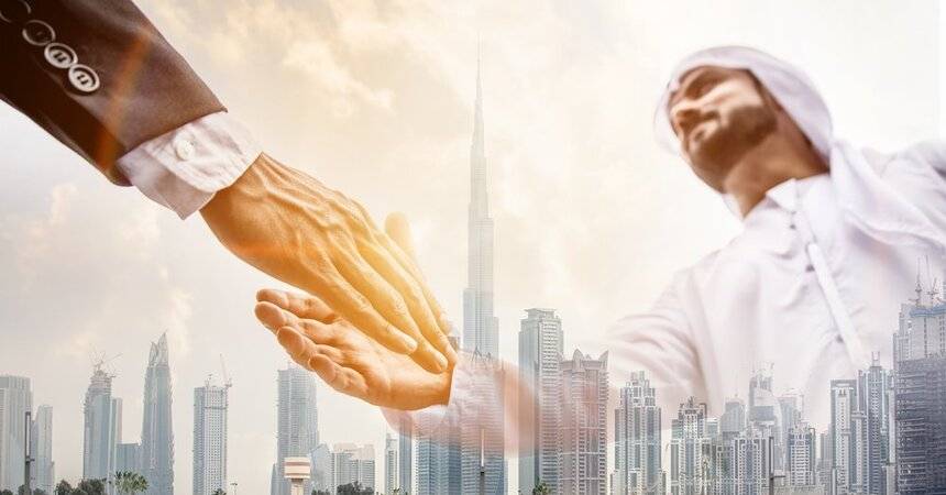 Two businessmen shaking hands over a Dubai skyline with the Burj Khalifa
