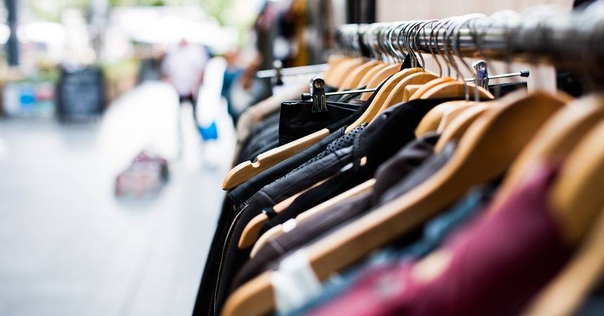 Rail of garments on wooden hangers in a clothing shop